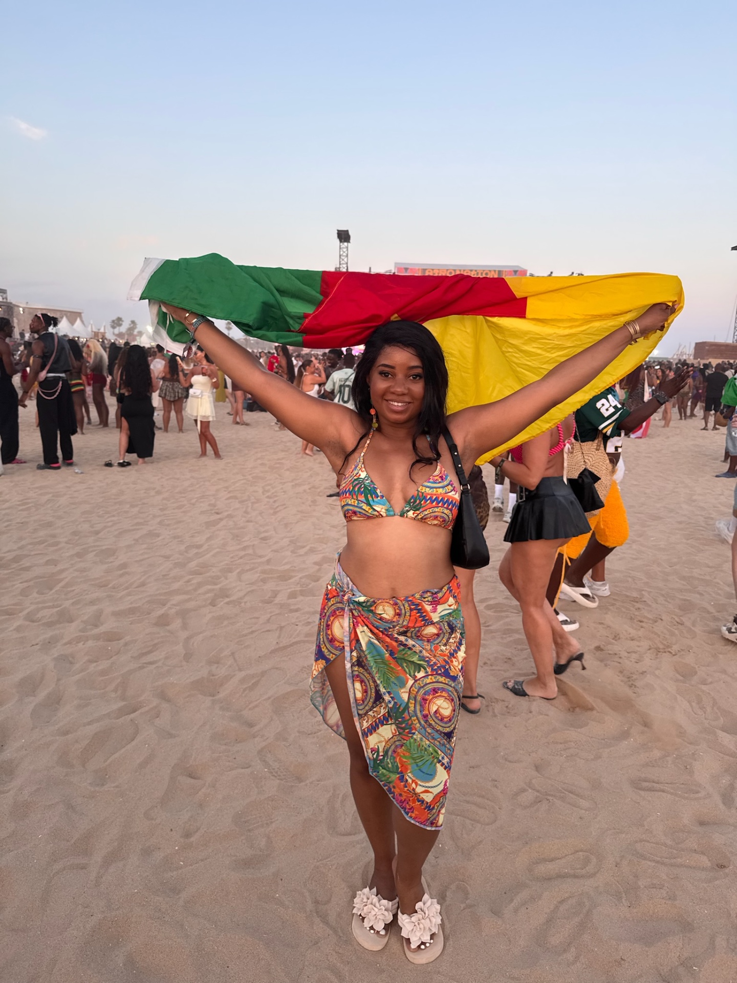 A festivalgoer holding up the Cameroon flag on the beach