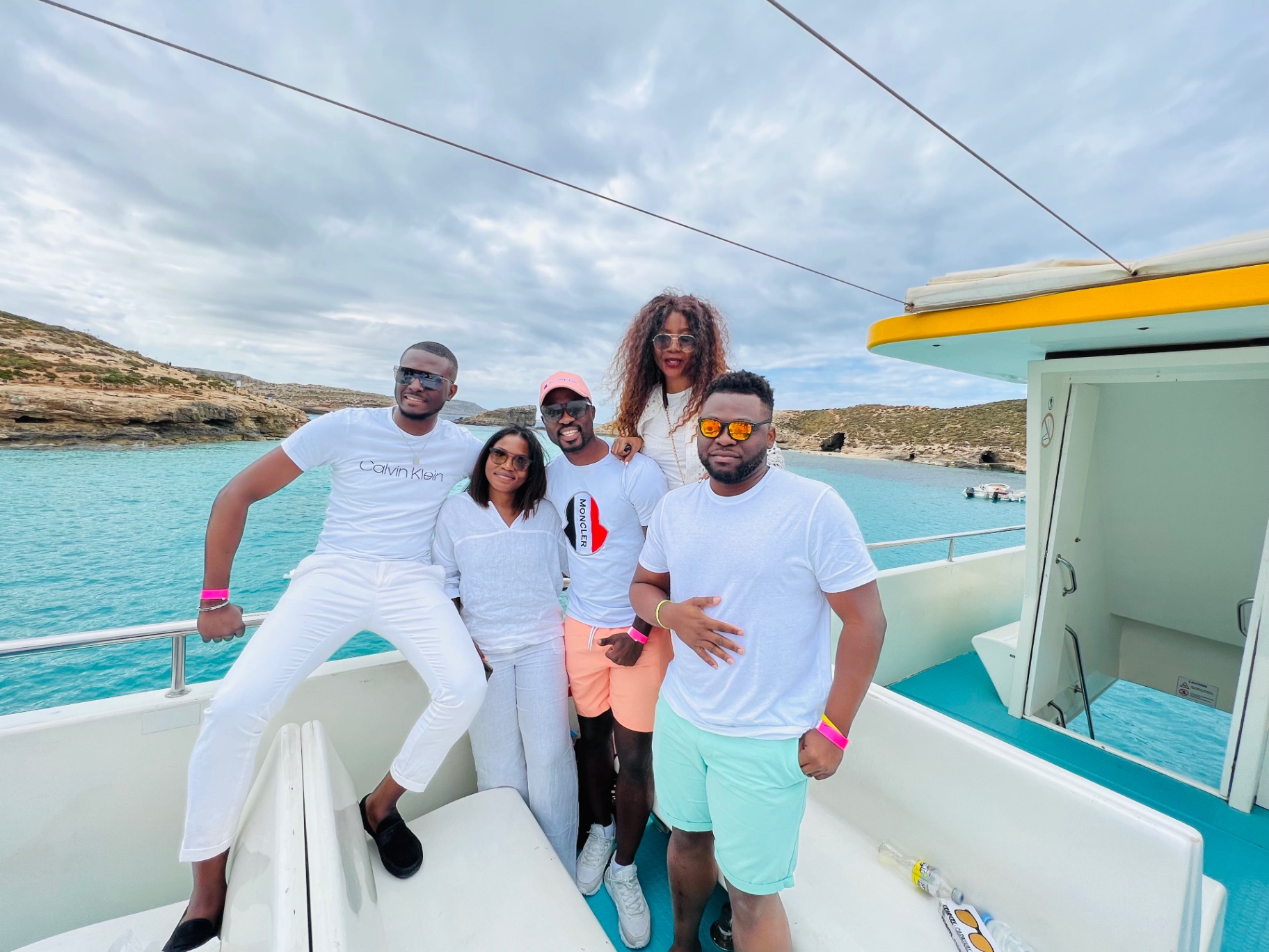 Cinq amis posent sur un bateau dans l'eau turquoise du Blue Lagoon, Comino
