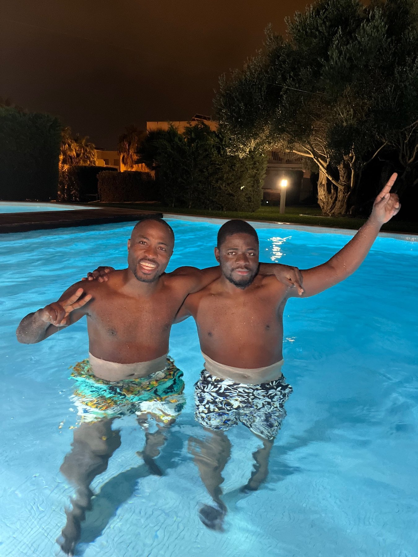 Deux amis profitent de la piscine d’une villa la nuit