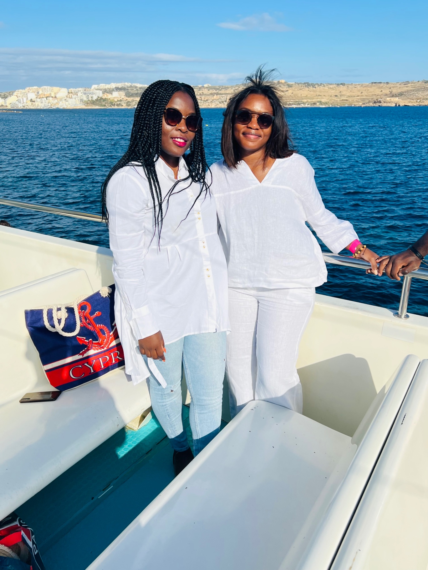 Deux amies en blanc sur un bateau le long de la côte