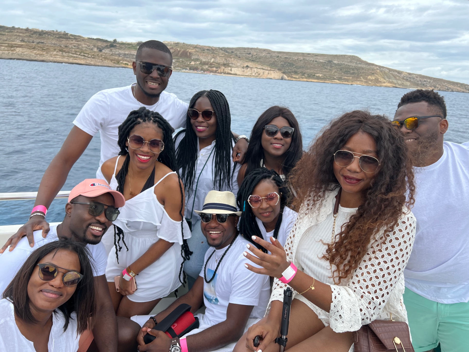 Un grand groupe d'amis en blanc sourient ensemble sur un bateau