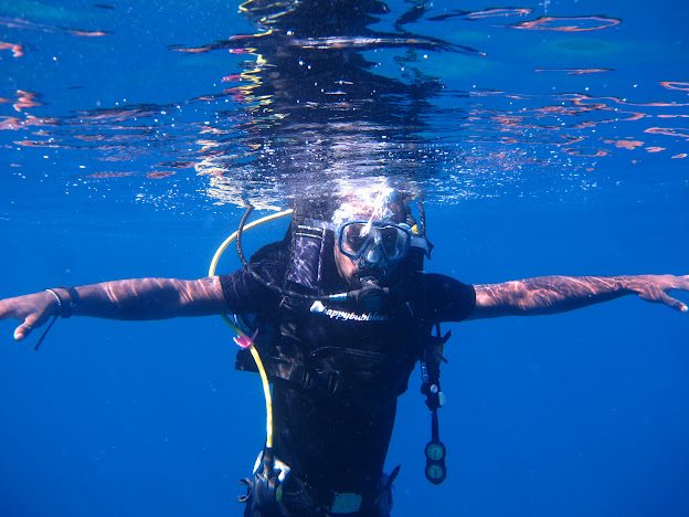 Rogers scuba diving in clear blue water, arms wide open