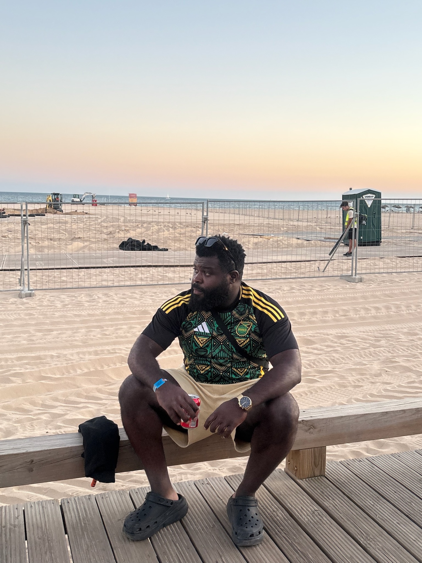 A traveler resting on a bench by the beach at sunset
