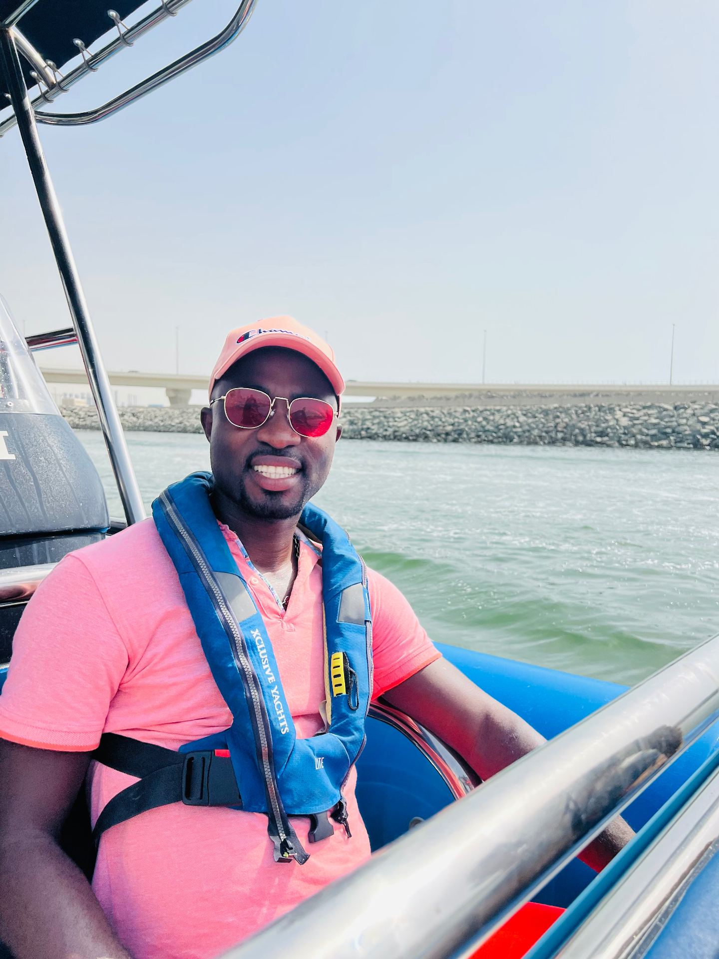 Rogers smiling on a boat at sea, wearing a pink cap and red sunglasses